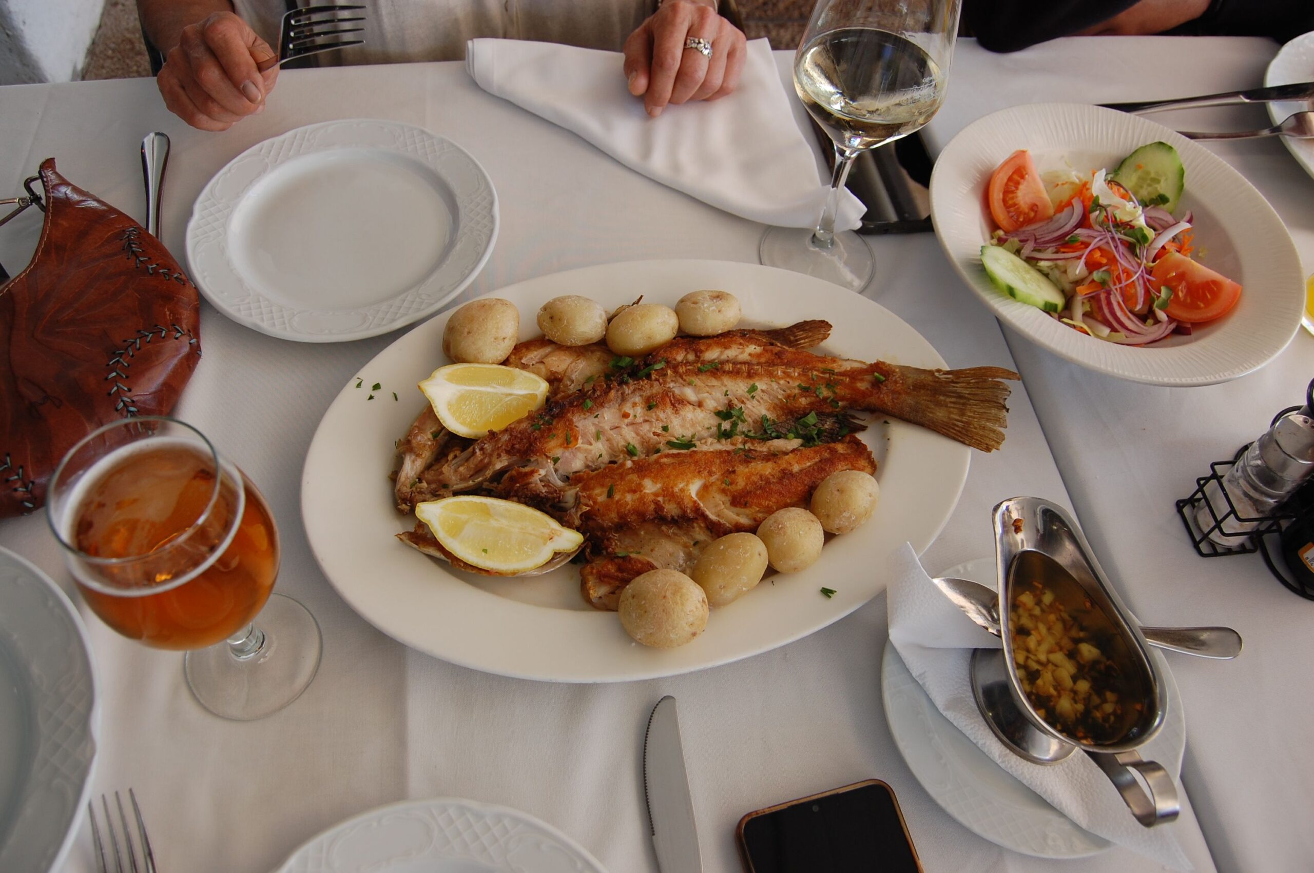 Pescado servido con papas arrugadas y limón en una mesa de restaurante
